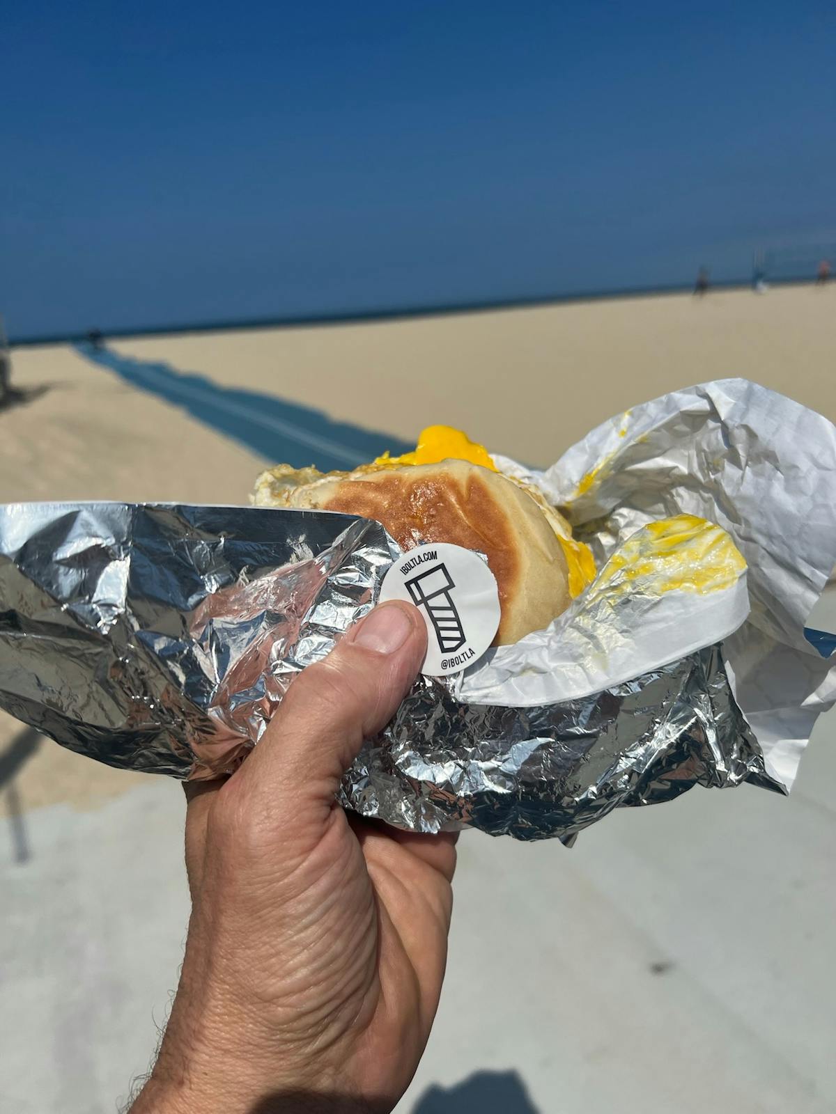 a hand holding a half eaten hot dog